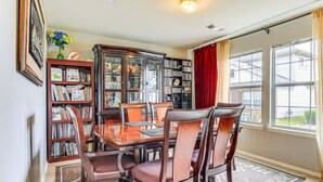 Une salle à manger avec une table et des chaises en bois, entourée d’étagères à livres.