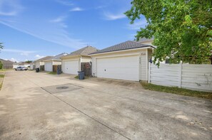 A residential street with single-story houses, each with a garage door and a small driveway. - Katy Family Home with Patio Pergola and Grill (Katy)