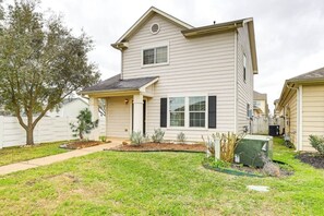A two-story house with a covered porch, a small garden, and a fenced yard.