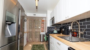 A modern kitchen with stainless steel appliances, a wooden countertop, and a black and white backsplash. - Spacious 3BR condo in Alexandria w/ 100" TV and free parking (Alexandria)