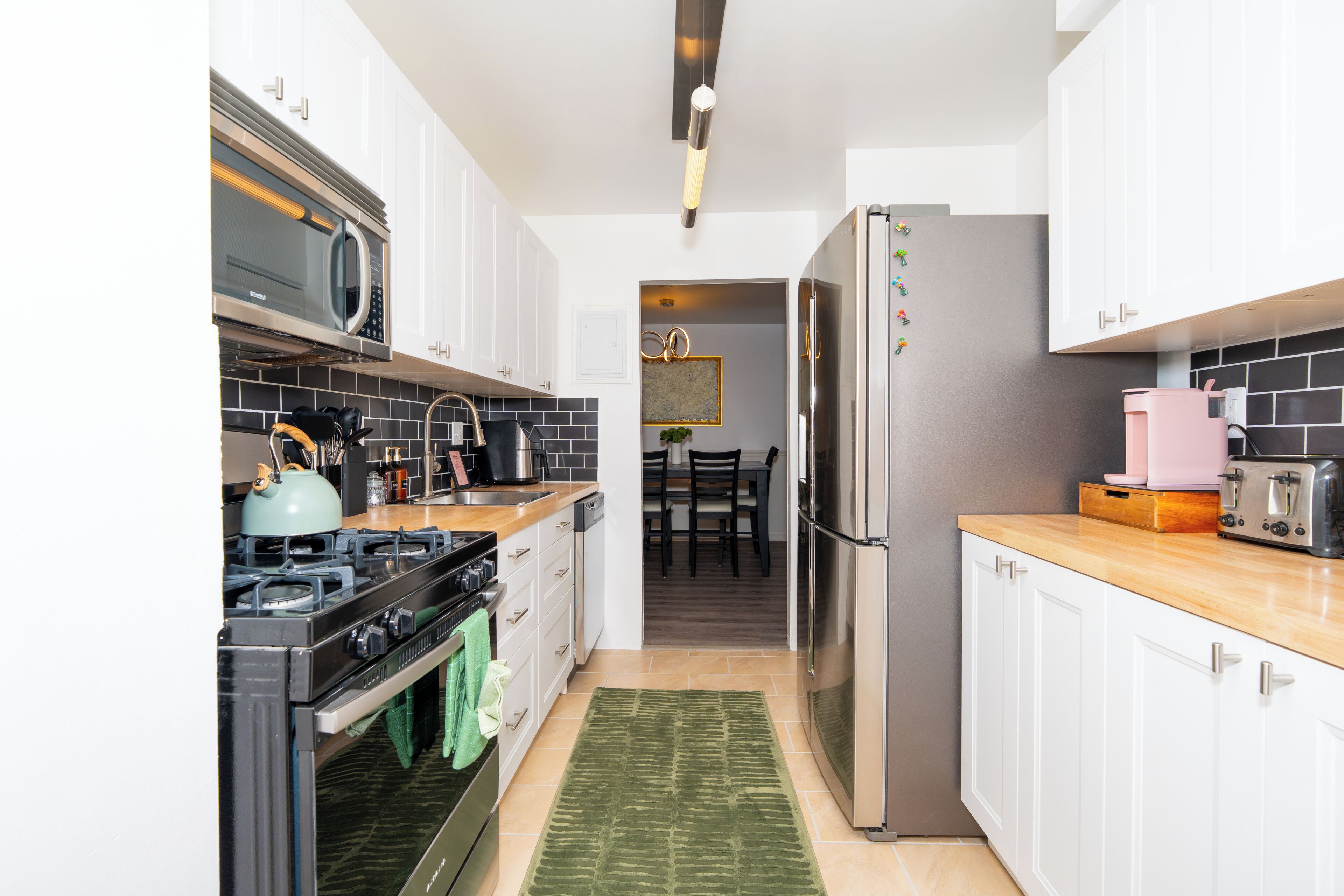 Eine moderne Küche mit weißen Schränken, einem Edelstahl-Kühlschrank, einer Mikrowelle und einem Gasherd.