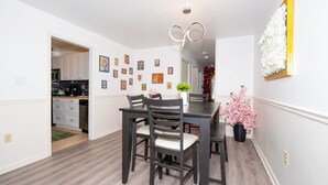 A dining area with a dark wooden table and chairs, a vase with flowers, and a wall decorated with framed pictures. - Spacious 3BR condo in Alexandria w/ 100" TV and free parking (Alexandria)