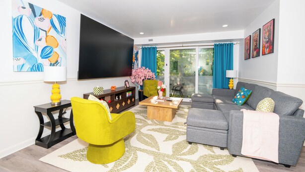 A modern living room with a sofa, armchair, coffee table, flat-screen TV, and artwork on the walls. - Spacious 3BR condo in Alexandria w/ 100" TV and free parking (Alexandria)