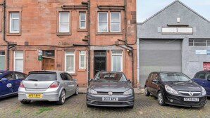 A multi-story building with a brick facade, a garage door, and several parked cars. - Edinburgh City Centre & Shore - Free Parking -WiFi (Edinburgh)