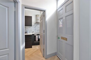 Ein Flur, der zu einer Küche mit modernem Design führt, mit einer Edelstahl-Dunstabzugshaube und einem Einbauofen.