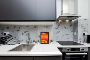 A modern kitchen with a stainless steel sink, a built-in oven, and a black induction cooktop. - Edinburgh City Centre & Shore - Free Parking -WiFi (Edinburgh)