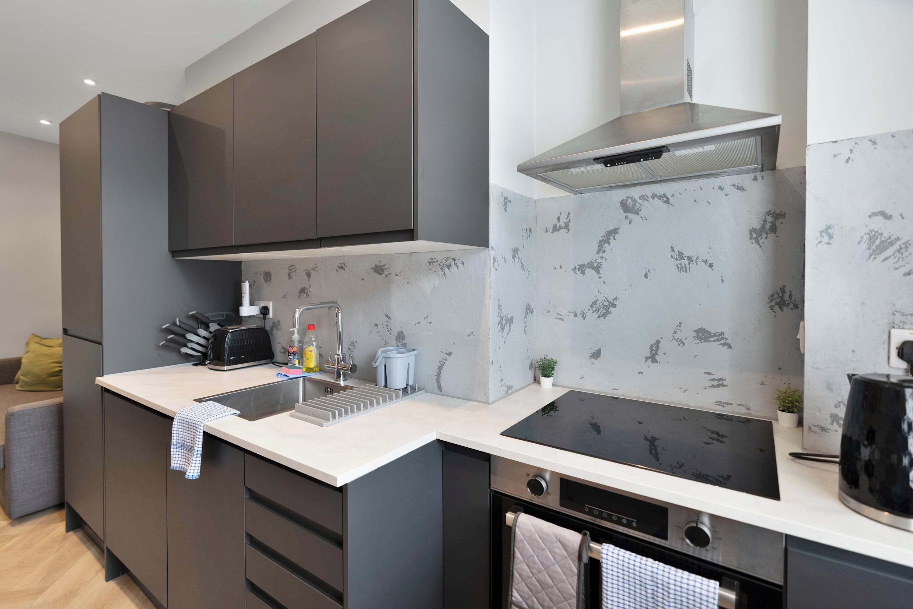 A modern kitchen with a built-in oven, a stainless steel range hood, and a large island with a sink.