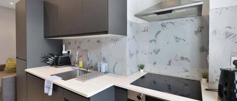 A modern kitchen with a built-in oven, a stainless steel range hood, and a large island with a sink.