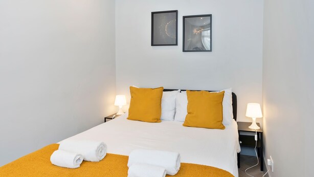 A hotel room with a bed, two bedside lamps, a nightstand, and two framed pictures on the wall. - Edinburgh City Centre & Shore - Free Parking -WiFi (Edinburgh)
