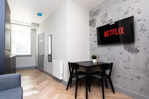 Un salon moderne avec un téléviseur à écran plat fixé au mur, une table à manger avec des chaises et un canapé.