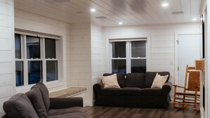 A modern living room with a dark brown sofa, a wooden coffee table, and a rocking chair. - The Lodge, Algonquin Woods (Perry)