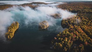 Ilmakuva metsäisestä alueesta, jossa on useita saaria, jotka ovat veden ympäröimiä. Joillakin saarilla on näkyvissä rakennelmia.