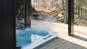 Ett bubbelbad på ett trädäck med utsikt över skogen.