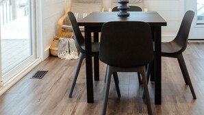 A dining area with a table, chairs, a window with a view, and a door. - Maple Haven, Algonquin Woods (Perry)