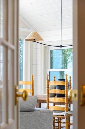 A room with a wooden dining table, chairs, and a hanging lamp. - Beach House on the Dunes (Norfolk County)
