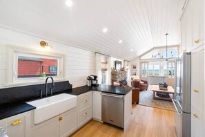 A compact kitchen with a sink, stove, and dining area. - Beach House on the Dunes (Norfolk County)