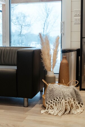 Ein modernes Wohnzimmer mit einem schwarzen Sofa, einer Vase mit Pampasgras, einem gewebten Korb und einer hohen Vase.