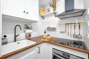 A modern kitchen with white cabinetry, a stainless steel range hood, and a wooden countertop. - Marbella Sky Retreat el Nido Suite (Marbella)