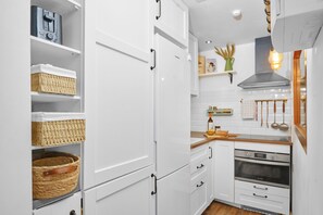 A modern kitchen with white cabinetry, a built-in oven, and a stainless steel range hood. - Marbella Sky Retreat, El Nido Suite (Marbella)
