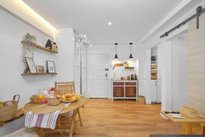 A modern kitchen with wooden cabinets, a dining table with a woven tablecloth, and a hanging plant. - Marbella Sky Retreat, El Nido Suite (Marbella)