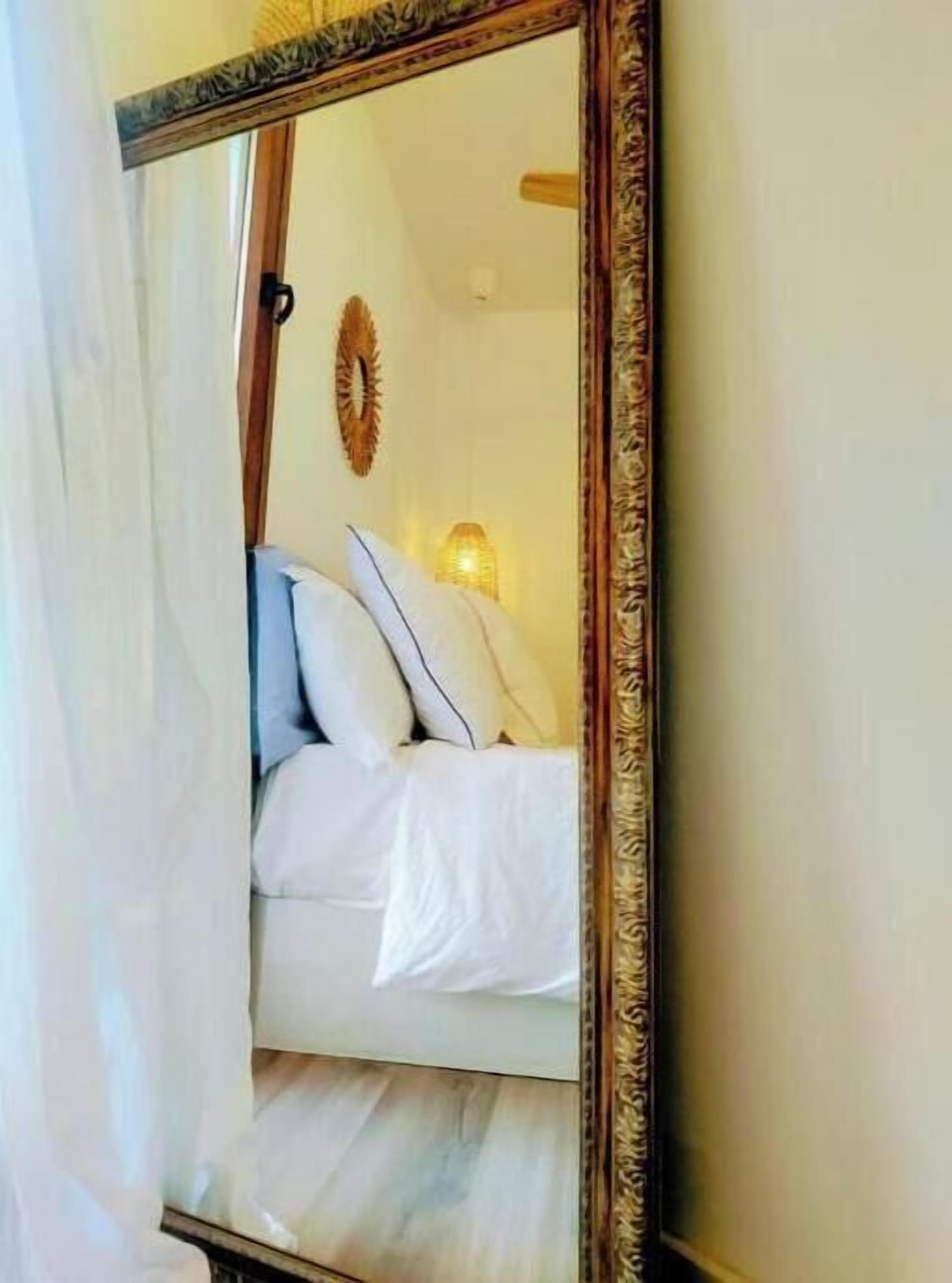 Un dormitorio con una cama, un espejo y una lámpara fijada a la pared.