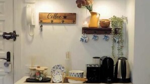 A kitchen area with two pendant lights, a coffee sign, a shelf with a vase and kitchen utensils, and a coffee machine. - Marbella Sky Retreat el Nido Suite (Marbella)