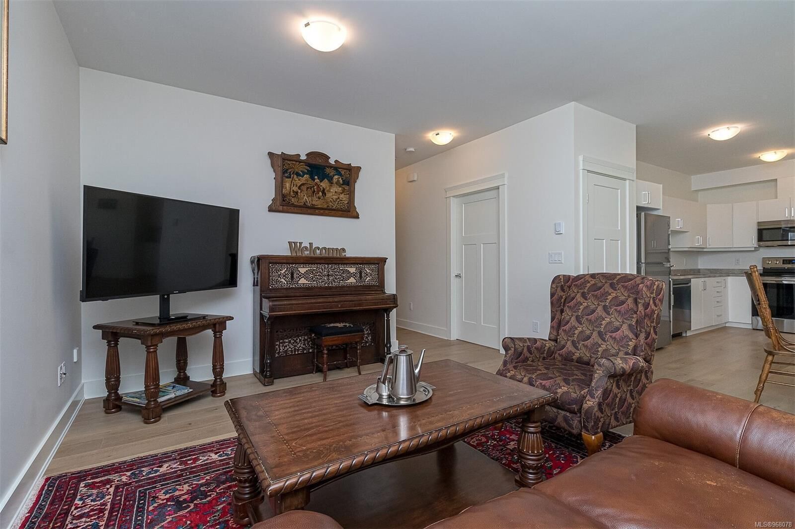 Living room features a patterned armchair, carved wooden coffee table, and an antique piano beneath a wall tapestry.