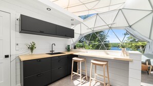 Eine moderne Küche mit Schwarz-Weiß-Farbgebung, einem großen Fenster und zwei hölzernen Barhocker.