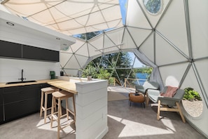 Une cuisine moderne dotée d’un grand îlot central, de tabourets de bar et d’un coin repas avec une table et des chaises.