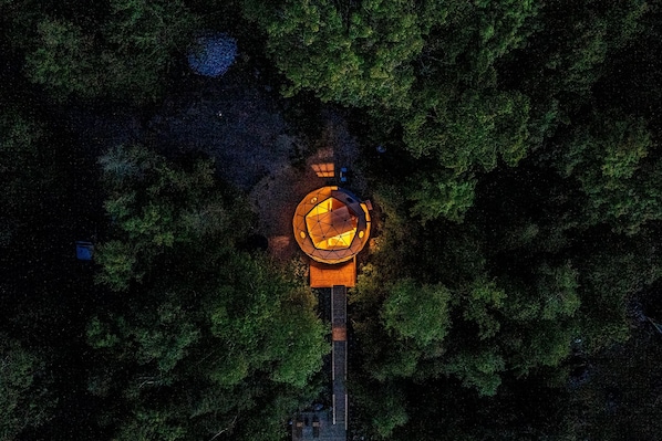 An aerial view of a circular building surrounded by dense forest.