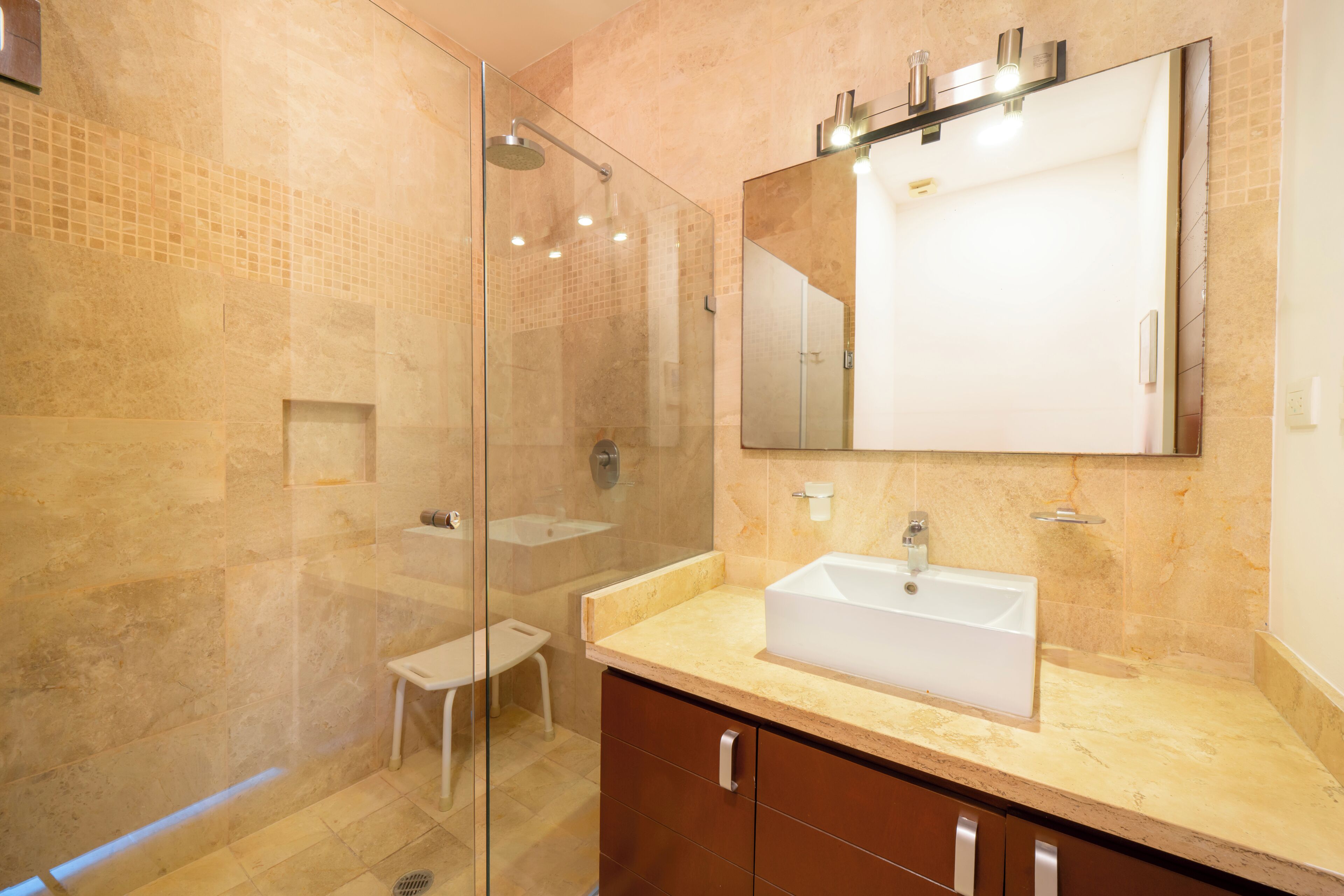A modern bathroom with a glass-enclosed shower, a sink, and a large mirror.