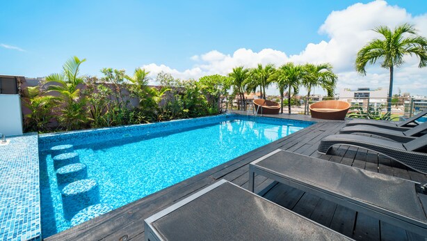 A rooftop pool with clear blue water, surrounded by palm trees and lounge chairs. - 2 Br condo with Rooftop Pool - Doca 303 (Playa del Carmen)