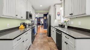 A kitchen with white cabinets, black countertops, and a tiled floor. - NEW - Sleeps 12, Fun Yard, Fire Pit Walk to Water! (Bristol)