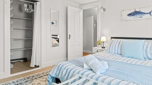 A bedroom with a bed, a wardrobe, a mirror, a nightstand with a lamp, and a wall with a fish painting. - NEW - Sleeps 12, Fun Yard, Fire Pit Walk to Water! (Bristol)
