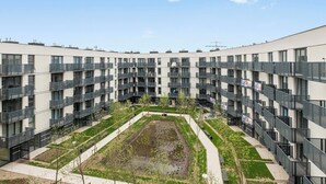Un edificio residencial de varios pisos con balcones, un patio central y cielo despejado.