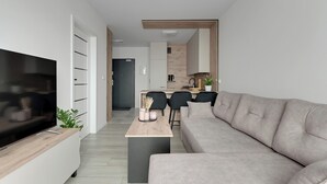 Una sala de estar moderna con un televisor de pantalla plana, un sofá, una mesa de centro y un comedor con sillas y una mesa.