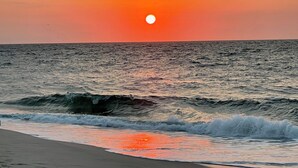 Un atardecer sobre el océano con olas acercándose a la costa.