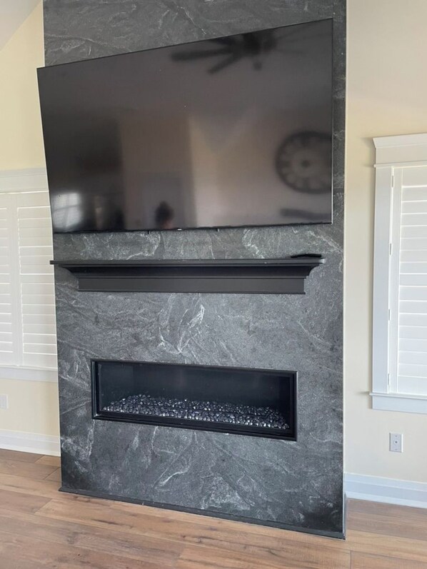 A modern fireplace with a flat-screen TV above it. - Beautiful bayfront 5-bedroom, 4.5-bathroom home with in-ground pool! (Lower Township)