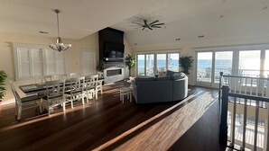Amplia sala de estar con mesa de comedor, sofá y un ventanal con vista al océano.