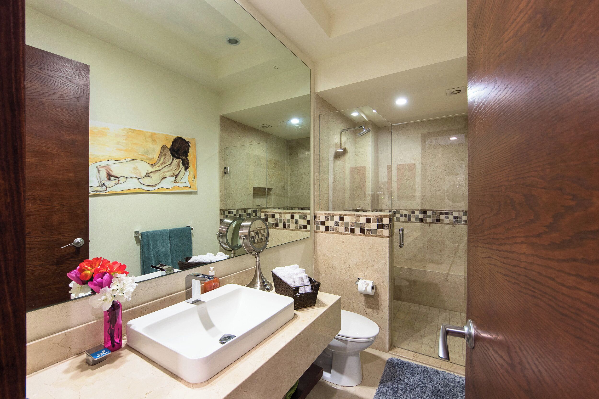 Un baño con un espejo grande, un lavabo, un inodoro y una ducha.