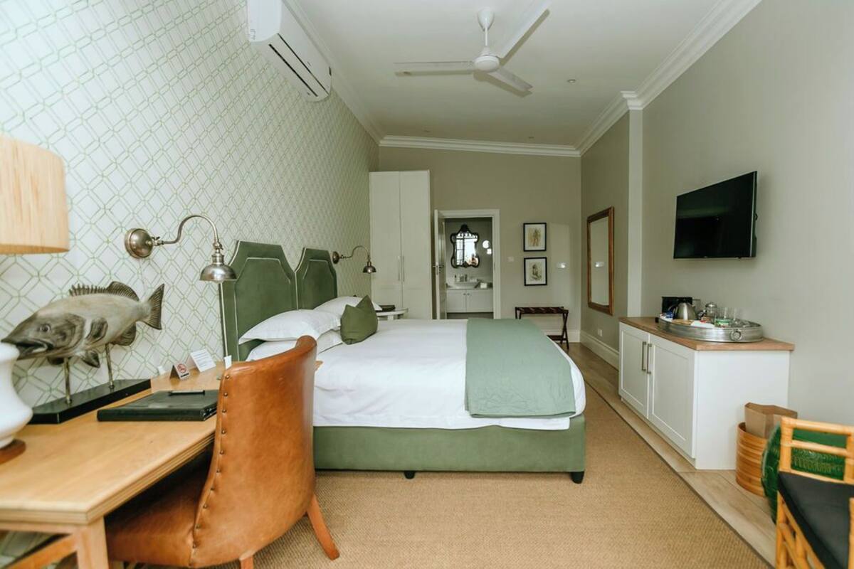 Un dormitorio con cama, escritorio, silla, televisor y kitchenette.