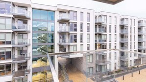 Un moderno edificio residencial de varios pisos con balcones, ventanas amplias y una escalera central.