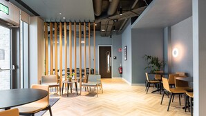 Un interior moderno con suelo de madera, varias mesas y sillas, y una señal de salida visible.