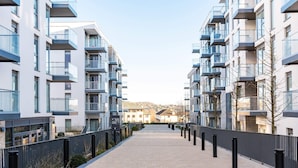 Un edificio residencial moderno con balcones, un sendero pavimentado y cielo despejado.
