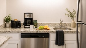A kitchen with a coffee maker, toaster, sink, and a dishwashing unit.