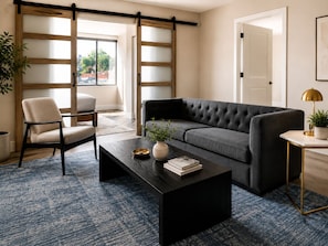 Ein Wohnzimmer mit Sofa, Sessel, Couchtisch und einer Schiebetür mit Blick.