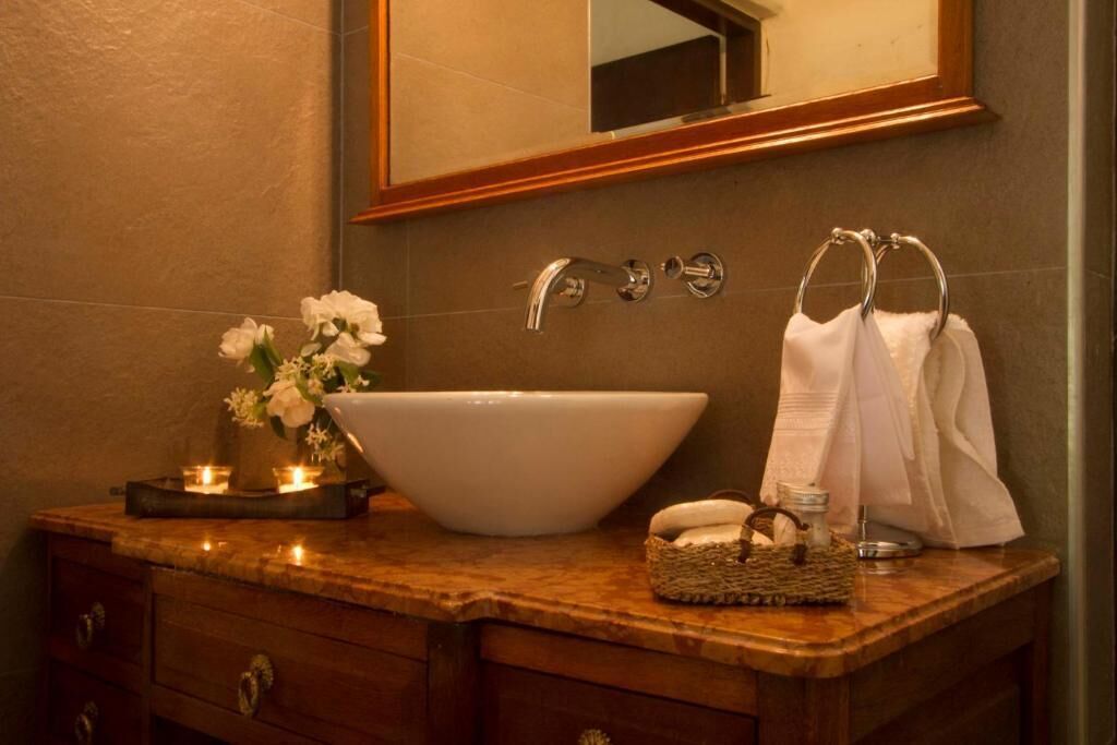 A bathroom with a large white sink, a mirror, a towel rack, and a small basket.