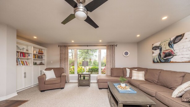 A living room with a sofa, coffee table, bookshelf, and a ceiling fan.