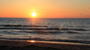 A sunset over a calm sea with waves gently lapping onto the shore.