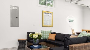 Ein modernes Wohnzimmer mit einem Ecksofa, einem kleinen Beistelltisch, einem Blumenstrauß und einer gerahmten Karte an der Wand.